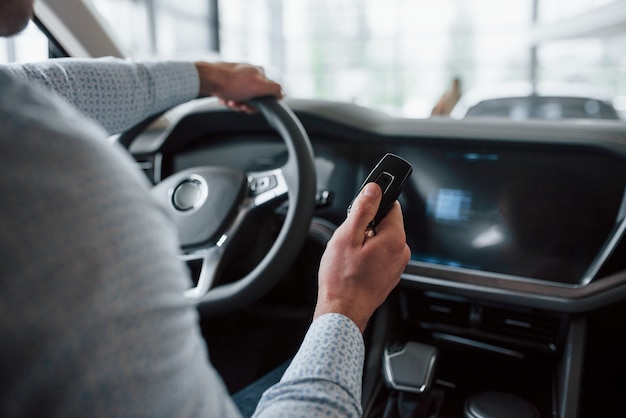 Alle opties testen. Man probeert overdag nieuwe auto in de salon. Een nieuw voertuig kopen