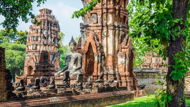 Alleen intact oud Boeddhabeeld onder de vernietigde beelden in het historische park van Ayutthaya, Thailand.