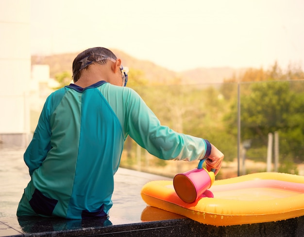 Alleen jongen speelt water gieten op het zwembad in het zwembad met zonlicht in de zomervakantie