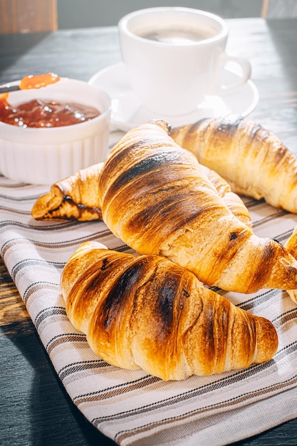 Alleen vers gebakken croissants met jam en koffie op tafel in de ochtendzon heerlijk ontbijtconcept