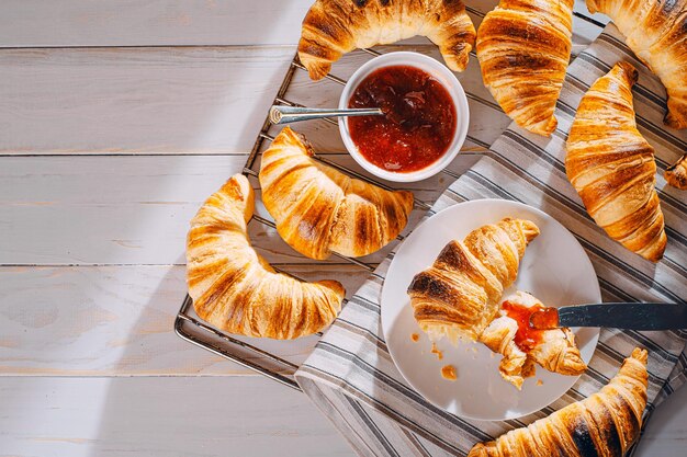 Alleen vers gebakken croissants met jam en koffie op tafel in de ochtendzon heerlijk ontbijtconcept