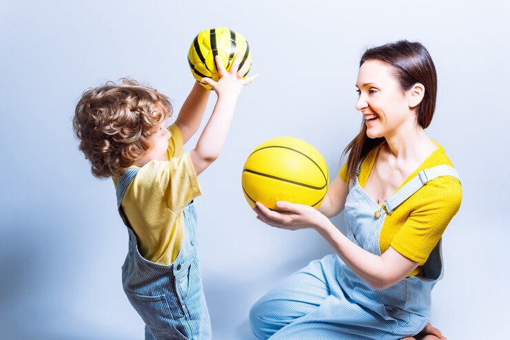 Alleenstaande ouder jonge volwassen moeder speelt met haar zoon met een basketbal en voetbal. concept spelen met kinderen. alleenstaande moeder. schoolsporten