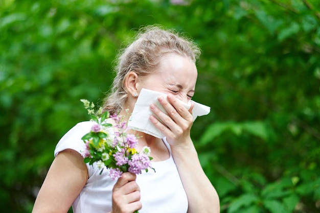 Allergie voor pollen, niezen van de vrouw met een boeket bloemen. Concept: seizoensgebonden allergie.