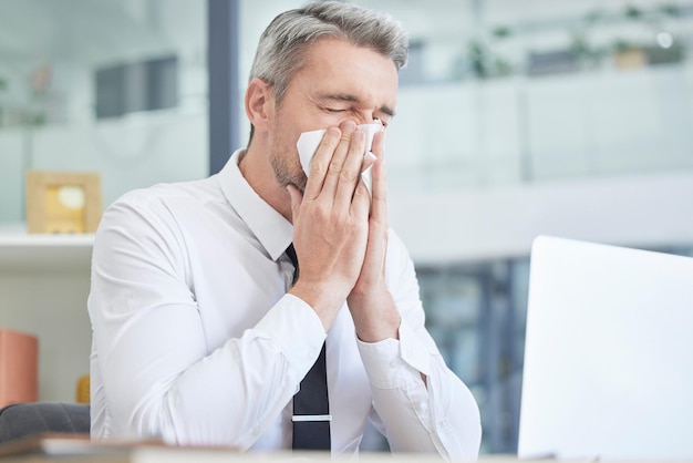 Allergies sick and businessman in his office cleaning nose with healthcare risk workplace compliance policy and management stress Dust bacteria and allergy of business or corporate man at a desk