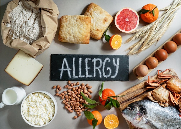 写真 灰色の背景にアレルギー食品のコンセプト、アレルゲン乳魚イチゴパン卵ピーナッツ柑橘類小麦の花など