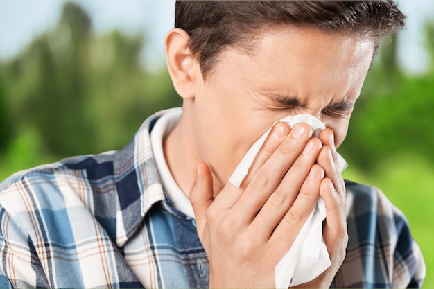 Allergy season concept, man with a handkerchief holding his nose