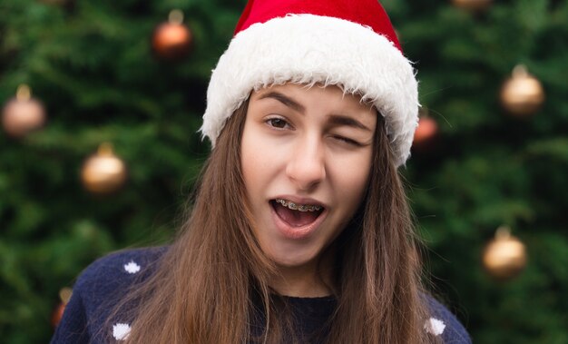 Alles komt goed voor Kerstmis. Sluit omhoog Portret van vrouw die een hoed van de Kerstman met emotie draagt. Tegen de achtergrond van een kerstboom.