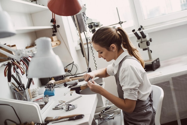 Alles over werk close-up portret van een vrouwelijke juwelier die aan een ring werkt bij