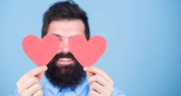 Alles wat hij nodig heeft is liefde Hipster die ogen bedekt met kleine hartjes Sexy valentijn man met liefdeskaarten Bebaarde man met rode harten Happy Valentijnsdag uiting geven aan zijn liefde kopie ruimte