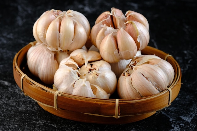 Allium sativum. a pile of whole garlic on a woven bamboo container. Garlic is a cooking spice.