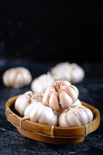 Allium sativum. a pile of whole garlic on a woven bamboo container. garlic is a cooking spice.