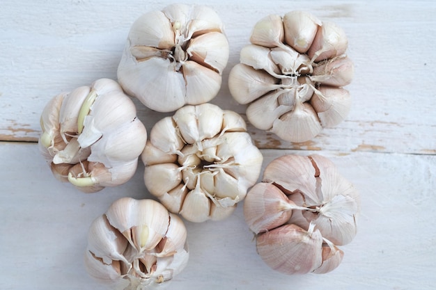 Photo allium sativum. whole piece of garlic on a white wooden table. cooking spice in asia, europe, africa