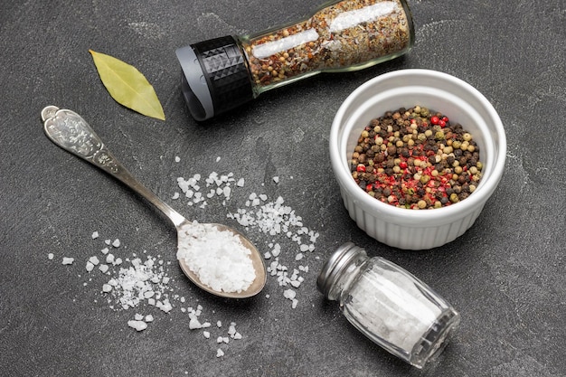 Allspice in bowl Salt in metal spoon Salt shaker and bay leaf