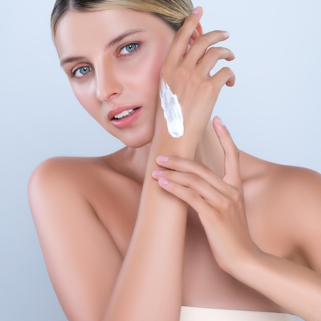 Alluring beautiful woman applying moisturizer cream on her hand for perfect skin