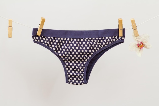 Alluring black panties on clothesline with clothespins and orchid flower in white background