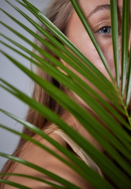alluring in good shape bewitching female model over 20s in sandy clothes cuddling the fern leave during the shooting process