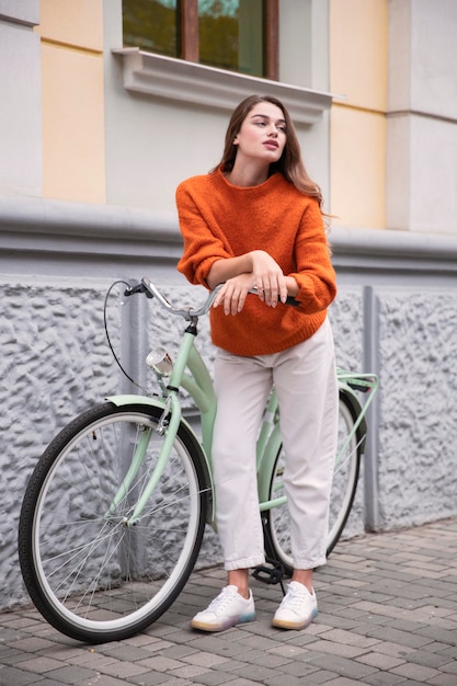 Очаровательная женщина позирует со своим велосипедом на улице
