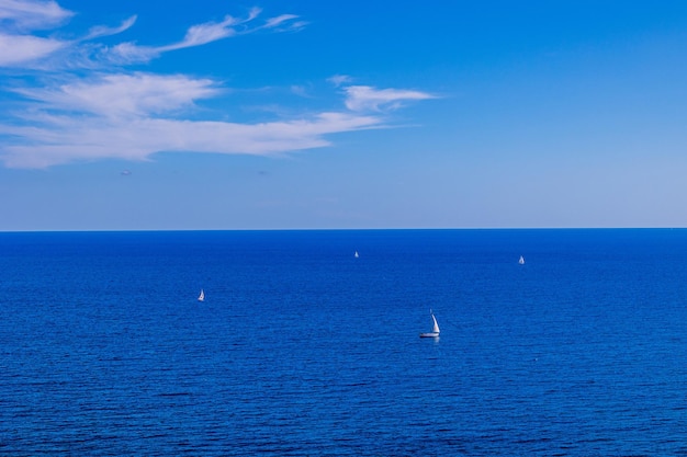 Голубой приморский пейзаж с водой и небом и парусными лодками