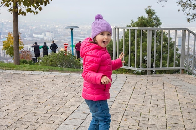 アルマトイ カザフスタン 11052022 小さな女の子が秋の公園で暖かい服を着て公園で踊っています。