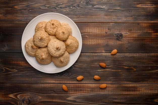 Almond biscuits on a white plate on a wooden background.