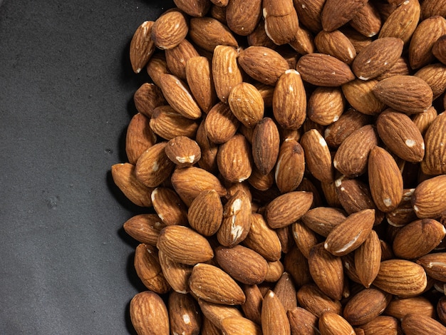 The almond in black plate on wood table for food and health  concept