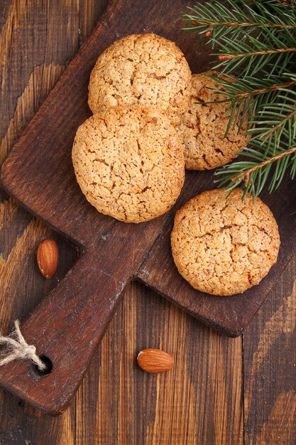 Almond cookie on a brown wooden background, the branches of spruce