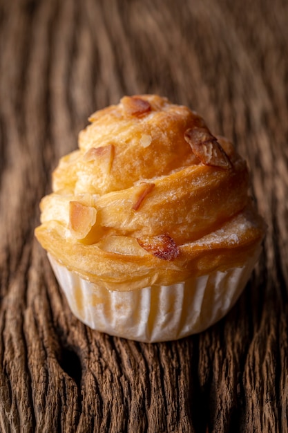 Almond cruffin with custard filling on rustic wood texture background, cruffin is hybrid of croissant and muffin