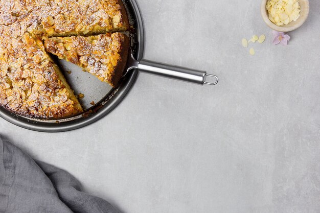 Almond homemade cake with sliced almonds crust and icing powder sugar on light gray concrete surface