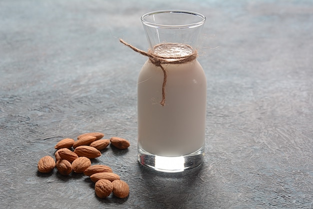 Photo almond milk in glass bottles with almonds on background.