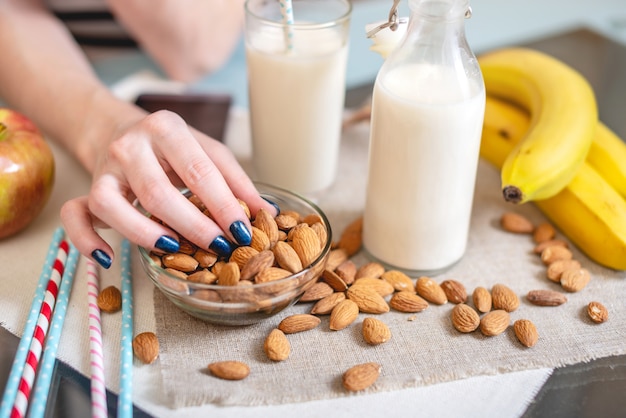 Almond milk in a glass Cup and fruit with scattered almonds on the kitchen table. Diet healthy vegetarian product