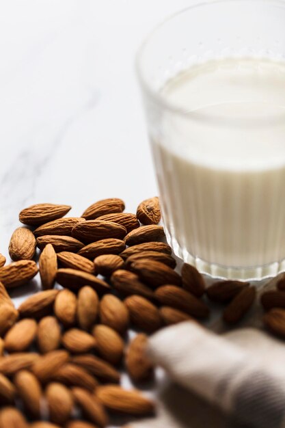 Almond milk in a glass surrounded by organic almonds