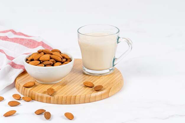 Photo almond milk in a glass with almond on a wooden table