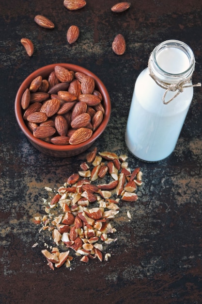 Almond milk and raw almonds in a bowl on a stylish shabby background