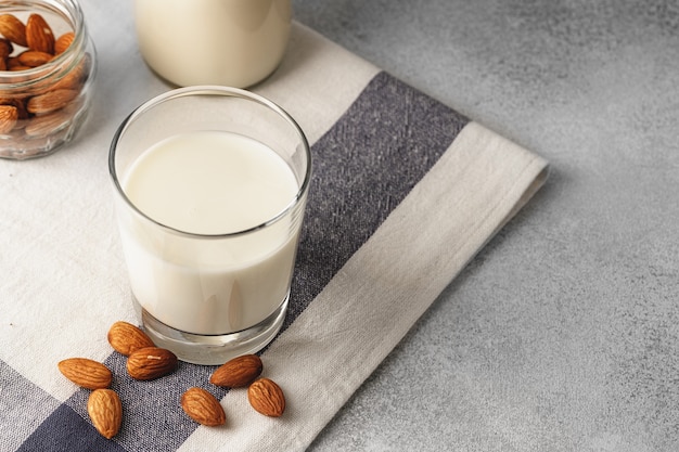 Almond milk with almond nuts surrounding the glass