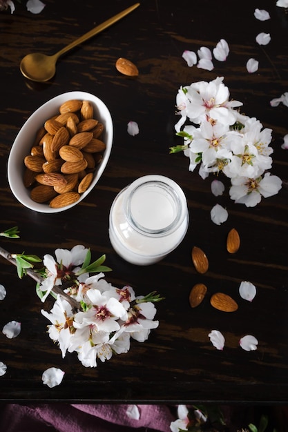 Foto latte di mandorle con mandorle e fiori di mandorla sul tavolo l'alternativa vegana al latte tradizionale