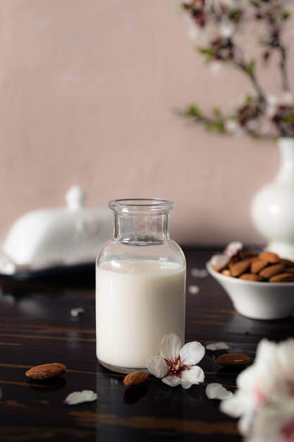 Foto latte di mandorle con mandorle e fiori di mandorla sul tavolo l'alternativa vegana al latte tradizionale