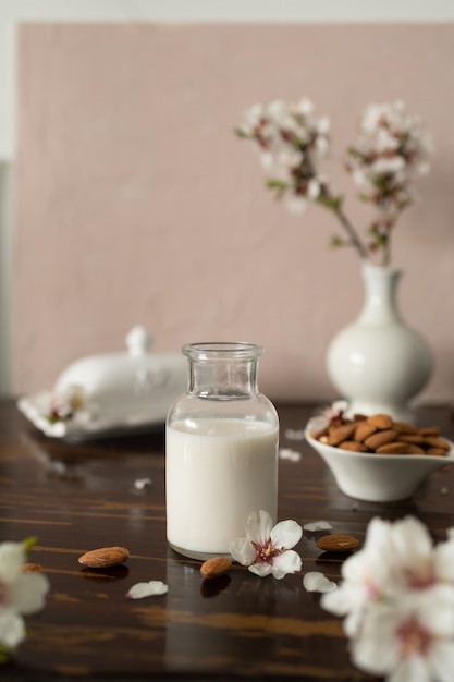 Foto latte di mandorle con mandorle e fiori di mandorla sul tavolo l'alternativa vegana al latte tradizionale