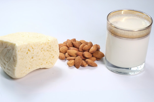 Almond nut, cheese and milk on white surface .