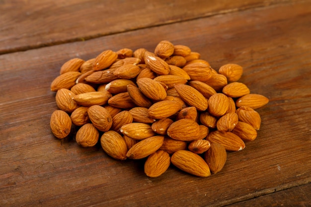 Photo almond nuts are sprinkled on a dark wooden table horizontal photo