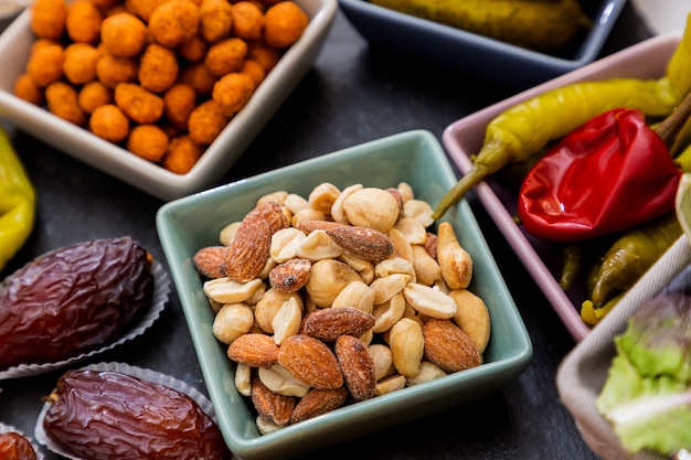 Almond Nuts, Peanuts, Spice Nuts, Sweet Peppers, Tong Da Tong in a small cup on a beautiful stone tray on the table