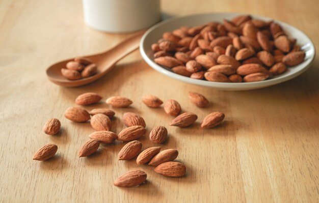 Almond nuts in white dish and wood spoon