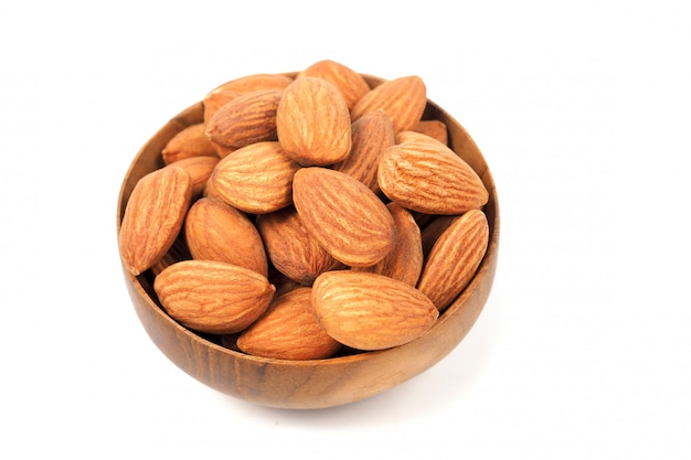 Almond seeds in wood bowl isolated on white background