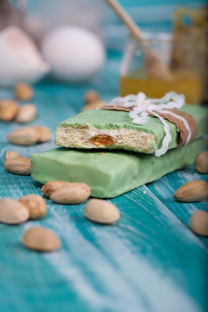 Almond turron covered by pistachio chocolate on a wooden surface. Closeup