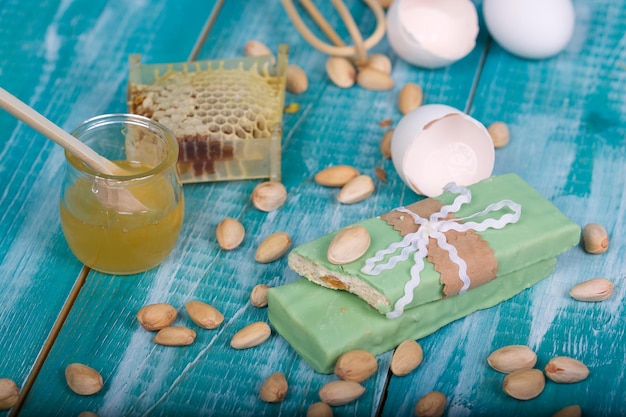 Almond turron covered by pistachio chocolate on a wooden surface. Closeup