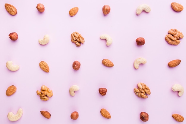 Almond, walnut, hazelnut and cashews flat lay. Nuts pattern on pink background, top view