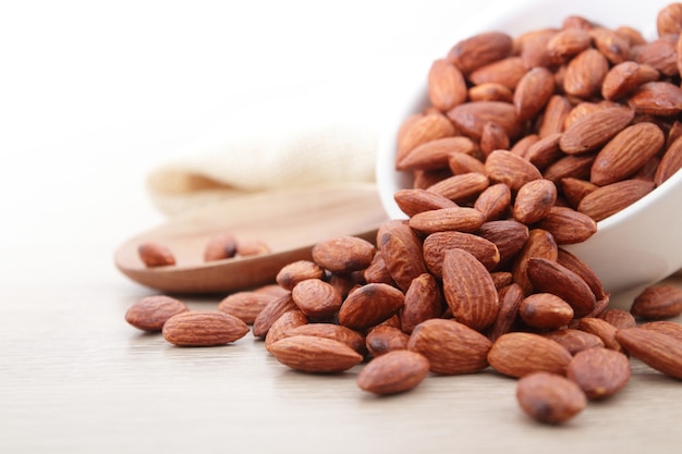 Almonds are in a white cup. Placed on a wooden floor. Food photography concept.