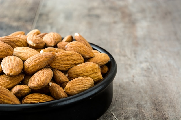 Almonds in black bowl on wooden table