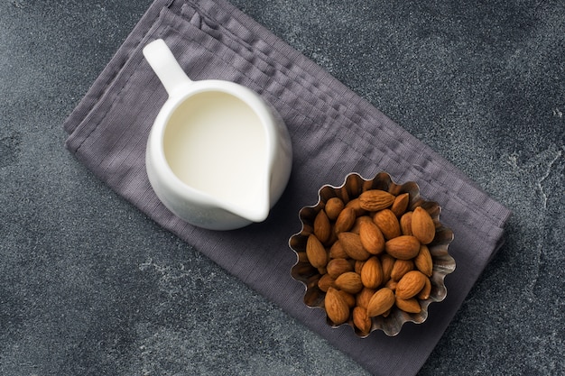 Almonds in a bowl and milk on the table.