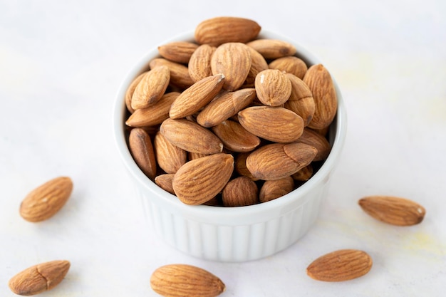 Almonds in bowl on wooden background