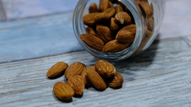 Almonds in a glass jar falling on the blue wood of the kitchen. close up view